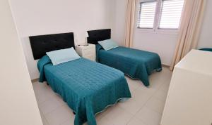 a room with two beds with green sheets and a window at Apartamento de la Playa II in Tías