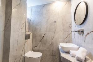 a bathroom with a sink and a toilet and a mirror at Olivia Apartment 2 in Pefkohori