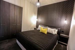 a bedroom with a bed with two yellow pillows at Indulge Apartments - CBD in Mildura