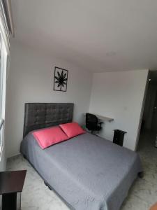 a bedroom with a large bed with a red pillow at Apartamento con la mejor ubicación y descanso in Armenia