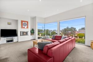 a living room with a red couch and a large window at Saltwater Serenity - Townhouse with a View in Torquay