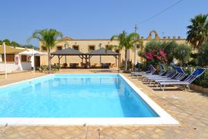 a swimming pool with lounge chairs and a building at Baglio Calia in Mazara del Vallo