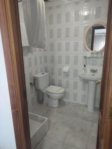 a white bathroom with a toilet and a sink at Pensión Rada in Solares