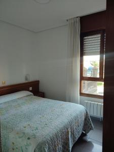 Schlafzimmer mit einem Bett und einem Fenster in der Unterkunft Pensión Rada in Solares