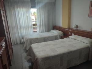 ein Hotelzimmer mit 2 Betten und einem Fenster in der Unterkunft Pensión Rada in Solares