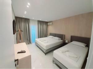una camera d'albergo con 2 letti e una scrivania di GB Rooms a Ksamil