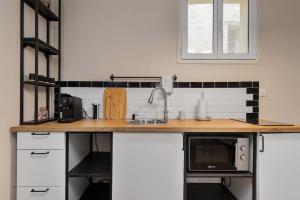 een keuken met een aanrecht met spoelbak en magnetron bij Appartement 2P Confort Hyper Centre & 100m de la plage in Dieppe +1 foto