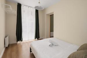 een wit bed in een kamer met een groot raam bij Appartement 2P Confort Hyper Centre & 100m de la plage in Dieppe