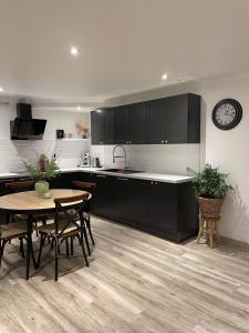 uma cozinha com armários pretos, uma mesa e um relógio em Maison avec cheminée et jardin près des commerces em Béziers