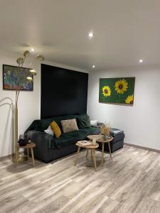 ein Wohnzimmer mit einem grünen Sofa und 2 Tischen in der Unterkunft Maison avec cheminée et jardin près des commerces in Béziers