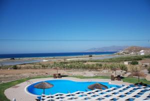 a view of a pool with umbrellas and the ocean at Koulas Pension - Red Lake in Agios Prokopios