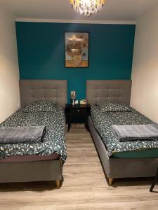twee bedden in een slaapkamer met een blauwe muur bij Maison avec cheminée et jardin près des commerces in Béziers