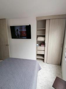 a bedroom with a bed and a tv on the wall at Apartamento con la mejor ubicación y descanso in Armenia
