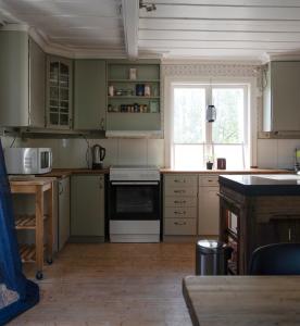 La cuisine est équipée de placards verts et d'une cuisinière blanche. dans l'établissement Lovely cabin with a beautiful view over Byske river, à Byske