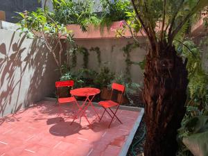 twee rode stoelen en een tafel naast een boom bij Xolo stays in Mexico-Stad