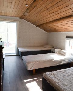Cette chambre comprend 3 lits et une grande fenêtre. dans l'établissement Lovely cabin with a beautiful view over Byske river, à Byske