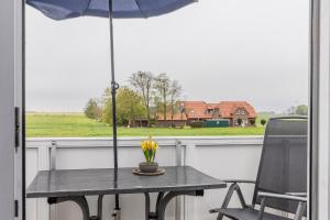 una mesa con sombrilla y una silla en el porche en 50030 Ferienwohnung Nordwind en Carolinensiel