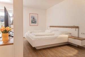 ein weißes Schlafzimmer mit einem Bett und einem Tisch in der Unterkunft 50177... in Harlesiel