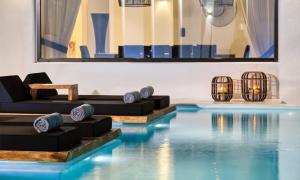 ein Pool mit blauem Wasser und schwarzen Möbeln in der Unterkunft Mbc Psarou Black Retreat 11 Bedrooms Mykonos in Psarrou