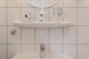 een witte badkamer met een wastafel en een spiegel bij 50139 Atlantis in Carolinensiel