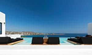 einen Pool mit zwei Liegestühlen und das Meer in der Unterkunft Mbc Psarou Black Retreat 11 Bedrooms Mykonos in Psarrou