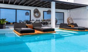 ein Swimmingpool mit Liegestühlen und einem Tisch in der Unterkunft Mbc Psarou Black Retreat 11 Bedrooms Mykonos in Psarrou + 32 Fotos