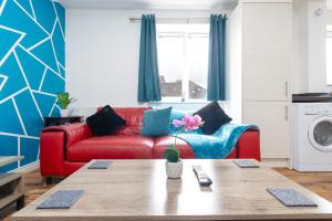 a living room with a red couch and a table at 2-BR Executive En-Suite Apartment by MBiZ in Coventry