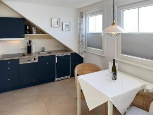a kitchen with blue cabinets and a white table at Südspitze 34 Whg. 26 in Wittdün