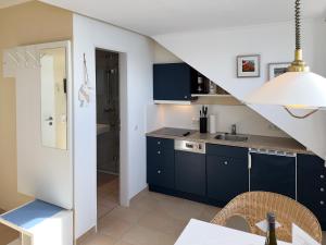 a kitchen with blue cabinets and a staircase at Südspitze 34 Whg. 26 in Wittdün