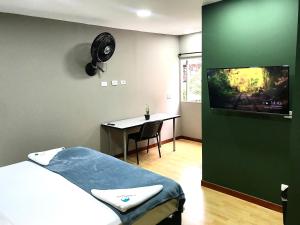 a hospital room with a bed and a desk with a tv at Poblado Park Guest House in Medellín