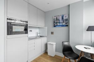 uma cozinha com armários brancos e uma mesa e cadeiras em Luxurious One Bedroom Apartment in Bond Street em Chelmsford