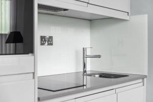 Luxurious One Bedroom Apartment in Bond Street في تشيلمسفورد: مطبخ مع حوض ودواليب بيضاء