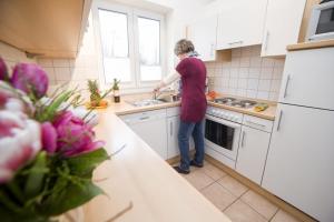 Uma mulher na cozinha a preparar comida. em Ferienhaus Saltkrokan em Otterndorf