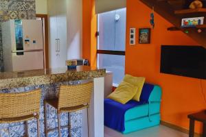 a kitchen with orange walls and a bar with a blue couch at Solaris 6 - duplex 2 quartos 10 mn a pé da praia in Imbassai