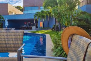 a resort pool with chairs and palm trees at Solaris 6 - duplex 2 quartos 10 mn a pé da praia in Imbassai