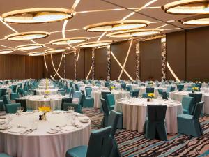 um salão de banquetes com mesas brancas e cadeiras azuis em Novotel New Delhi Aerocity- International Airport em Nova Deli