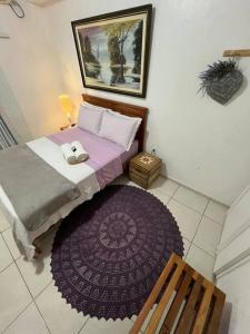 1 dormitorio con cama y alfombra morada en Suíte Lavanda Cama & Café - Centro, Marechal Floriano-ES, en Marechal Floriano