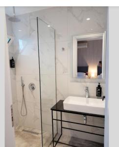 La salle de bains est pourvue d'un lavabo et d'une douche en verre. dans l'établissement GB Rooms, à Ksamil