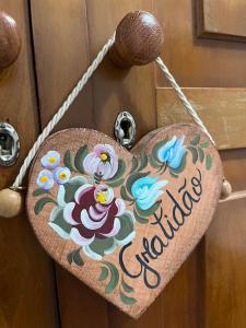 un cartello di legno a forma di cuore con fiori su una porta di Cantinho Ítalo-Germânico Hospedagem - Suíte Lavanda - Centro, Marechal Floriano-ES a Marechal Floriano