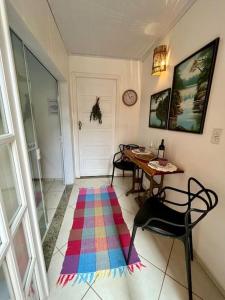 Habitación con mesa y alfombra colorida en el suelo en Suíte Lavanda Cama & Café - Centro, Marechal Floriano-ES, en Marechal Floriano