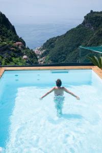 uma mulher numa piscina com vista para o oceano em Il Paradiso sul Mare Apartment em Scala