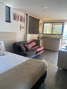 a bedroom with a bed and a couch and a kitchen at Apartamento con hermosa vista 502 in Ibagué