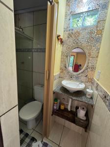 uma casa de banho com um WC, um lavatório e um espelho. em Chalé Maria Bonita - Ilha Grande, RJ em Angra dos Reis