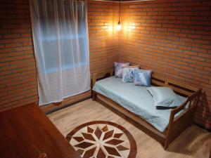 um pequeno quarto com uma cama numa parede de tijolos em Chalé Bienen Garten em Pomerode