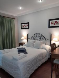 a bedroom with a large white bed with green curtains at Hotel Azul Junin in Junín