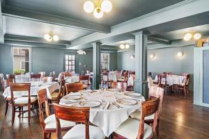 una sala da pranzo con tavoli e sedie bianchi di Majestic Hotel a Ocean Grove