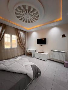 1 dormitorio con 1 cama grande y TV en el techo en Hotel Eloued فندق الوادي, en Tiksebt