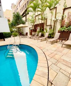 una piscina con sillas y un edificio en 205 Flat/Studio Elegance Jardins- Cozinha Completa, en São Paulo
