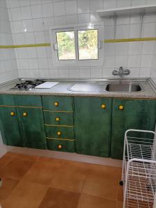 a kitchen with green cabinets and a sink at El Palomar Rooms Tarifa in Tarifa +51 photos