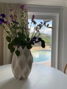 a white vase with purple flowers sitting on a table at Pedacinho de Mundo Douro in Passinhos de Cima
